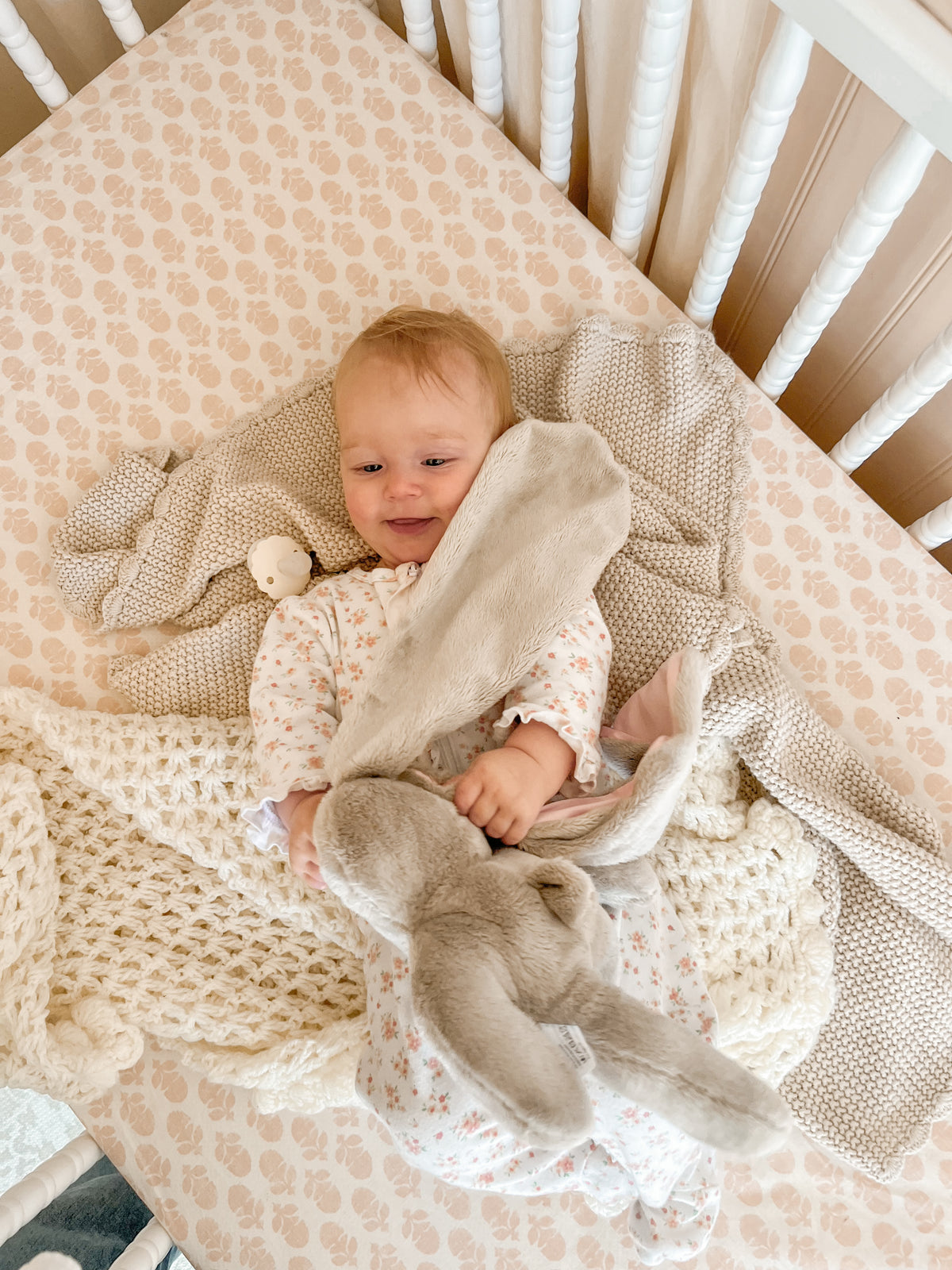Baby resting in a crib while holding a soft Hoppy baby lovey bunny, providing comfort and soothing during nap time.